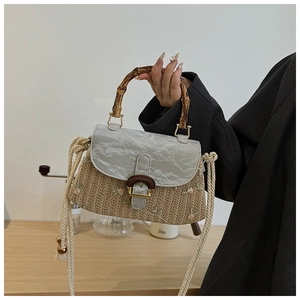 Detail of straw woven handbag with bamboo handle, floral embroidery and textured flap
