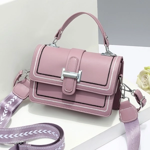 Elegant mauve crossbody bag with a wide geometric strap on modern geometric stands