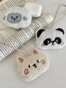 Tre simpatici ciondoli in peluche di animali tra cui agnello, panda e gatto su libri