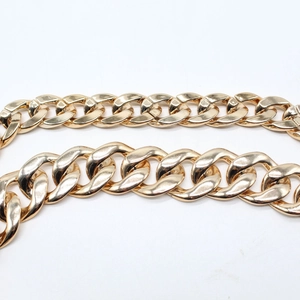 Macro shot of wide gold curb chain detail with polished metallic finish on fedora hat