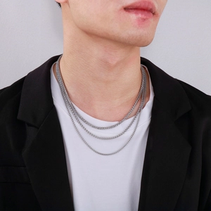 Three-layer stacked wheat link chains in stainless steel worn with a black suit jacket