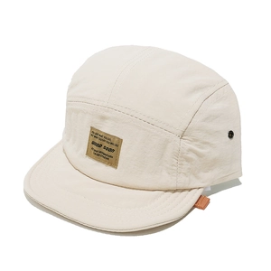 Detail of five-panel cream camper hat with woven label and metal side eyelets