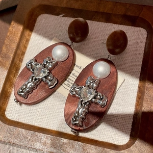 Gros plan de boucles d'oreilles croix en bois vintage avec strass et perles
