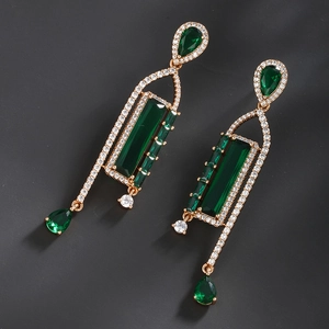 Macro detail of emerald drop earrings with sparkling crystals and gold plating
