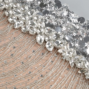 Detail of silver sequins and rhinestone tassels on a nude mesh evening dress