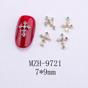 Vista macro di ciondoli per unghie a croce dorata 7x9mm con cristalli AB e perle su unghie rosse