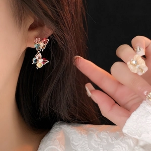 Elegante Goldohrringe mit bunten Zirkon-Schmetterlingsanhängern an einem Model