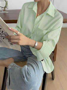 Detail of light green striped long sleeve shirt with buttoned collar and chest pocket