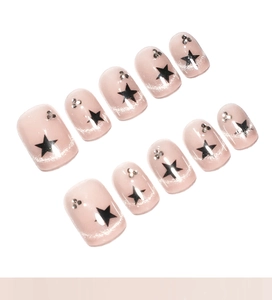 Close-up of pink cat eye nails with black stars and small rhinestones on white background