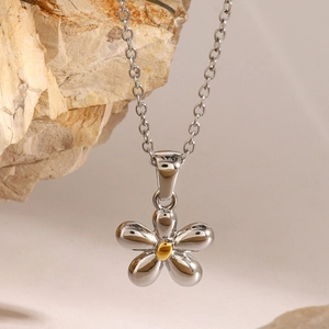 Close-up of a silver flower pendant with a gold center on a stainless steel necklace
