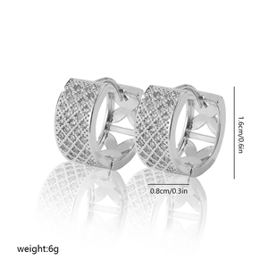 Macro detail of silver hoop earrings with hollow grid pattern and zircon stones