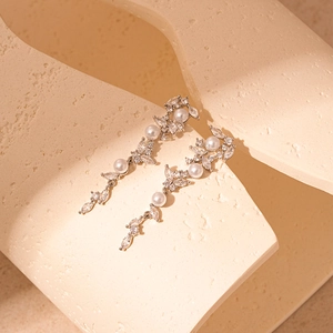 Detailed view of silver leaf tassel earrings with white pearls and sparkling zircons