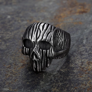 Vintage silver punk skull ring with textured metal finish on a dark stone background