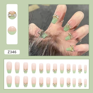 Detail of long ballerina press-on nails with bow rhinestones and green French tips