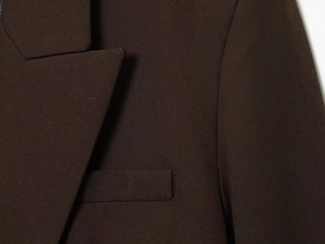 Detail of the coffee brown blazer showing notch lapel and pocket stitching craftsmanship