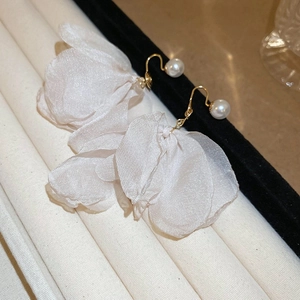 Detail of white mesh flower earrings with small pearl and gold hook on a stand
