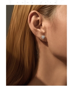 Close-up of heart-shaped moissanite stud earrings on ear with shimmering halo detail