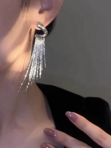 Close-up of silver geometric tassel earrings showing shimmering metal chains on ear