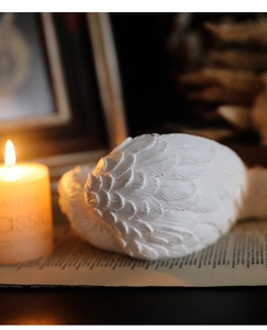 Close-up of white resin angel wings decor with intricate feather texture on vintage books