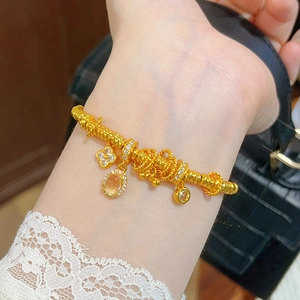 Detail of 24k gold flower bracelet with clover and oval gemstone charms on wrist