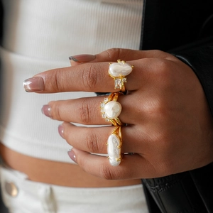 Detail of baroque pearl rings with gold metal and sparkling zircon on a model hand