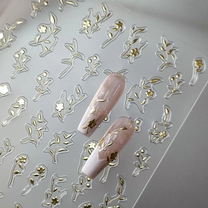 Self-adhesive gold floral nail art stickers with botanical designs on nude pink manicures