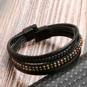 Detailed macro view of multi-layer black braided leather bracelet with mixed metal studs