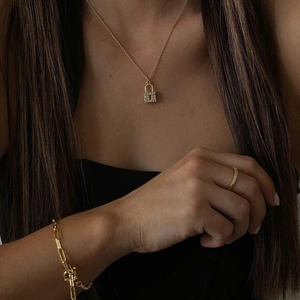 Close-up of 18k gold plated lock pendant necklace and sparkling zircon ring set on model