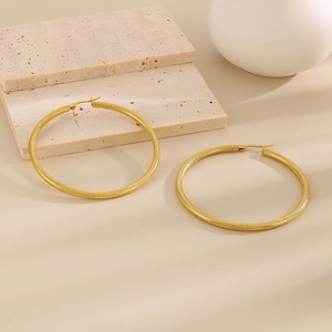 Dettaglio di grandi orecchini a C placcati in oro con finitura a trama intrecciata