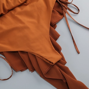 Detail of caramel halter dress featuring ruffle layers and slim tie strap texture