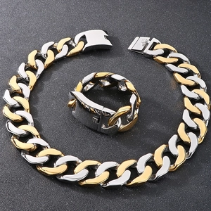 Detailed view of silver and gold Cuban link necklace and matching ring on black texture
