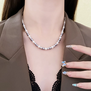 Close-up of a dual-tone pearl necklace featuring light and dark pearls on a model's neck