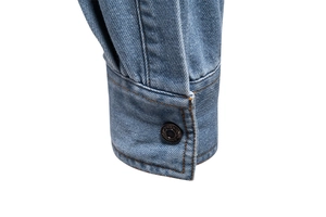 Vue détaillée du poignet de chemise en jean délavé avec couture et bouton en métal