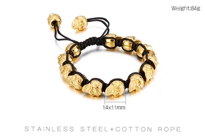 Close-up of golden stainless steel skull beads on a black braided cotton rope bracelet