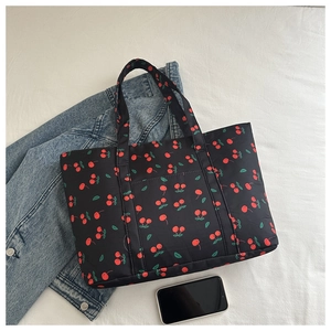Flat lay of black cherry print tote bag styled with denim jacket and mobile phone