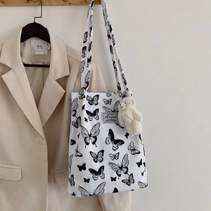 Detailed shot of a canvas tote with butterfly prints and a plush bear pendant