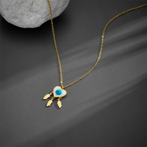 Golden heart necklace with evil eye pattern and leaf tassels on a dark background