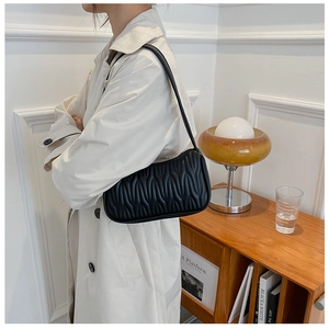 Side view of model wearing a black quilted PU leather shoulder bag in a minimalist setting