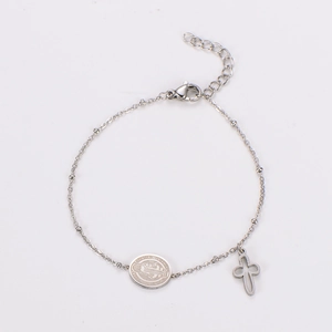 Close-up of Saint Benedict medal and hollow cross charms on stainless steel bracelet
