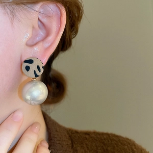 Détail macro de boucles d'oreilles léopard avec une perle blanche sur un modèle