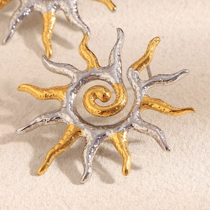 Macro view of textured dual-tone sun-shaped 18K gold and silver geometric stud earrings