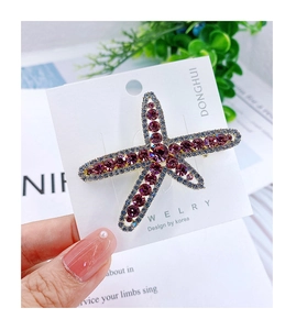 Detailed close-up of a starfish hair clip with purple and blue crystals on a gold base
