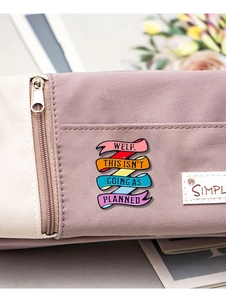 Detail showing colorful enamel ribbon pin with text on purple canvas backpack