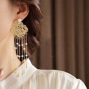 Detail of gold flower cloud earring with dangling pearl tassels worn by a model