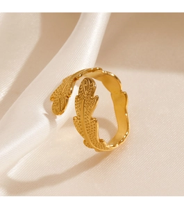 Macro shot of gold leaf feather ring with textured dots on soft white silk fabric