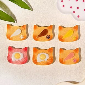 Flat lay of miniature resin cat-shaped toast charms with cute food-themed toppings