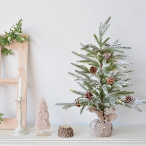 Mini PE cedar Christmas tree with warm lights and burlap base on a cozy winter tabletop
