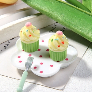 Close-up of miniature resin yellow cupcakes with pink pearls on decorative tray