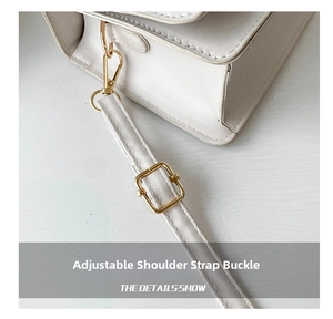 Detailed close-up of golden metal shoulder strap adjustment buckle on a white leather bag