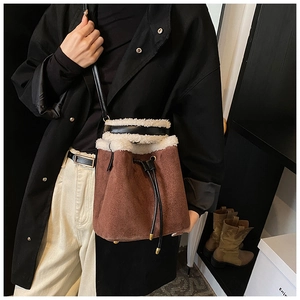Close-up of brown suede bucket bag with white faux fur trim and adjustable drawstring